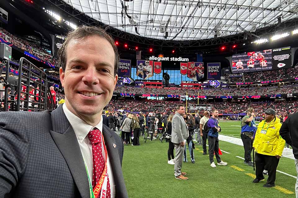 A man poses for a photo on a football field. 