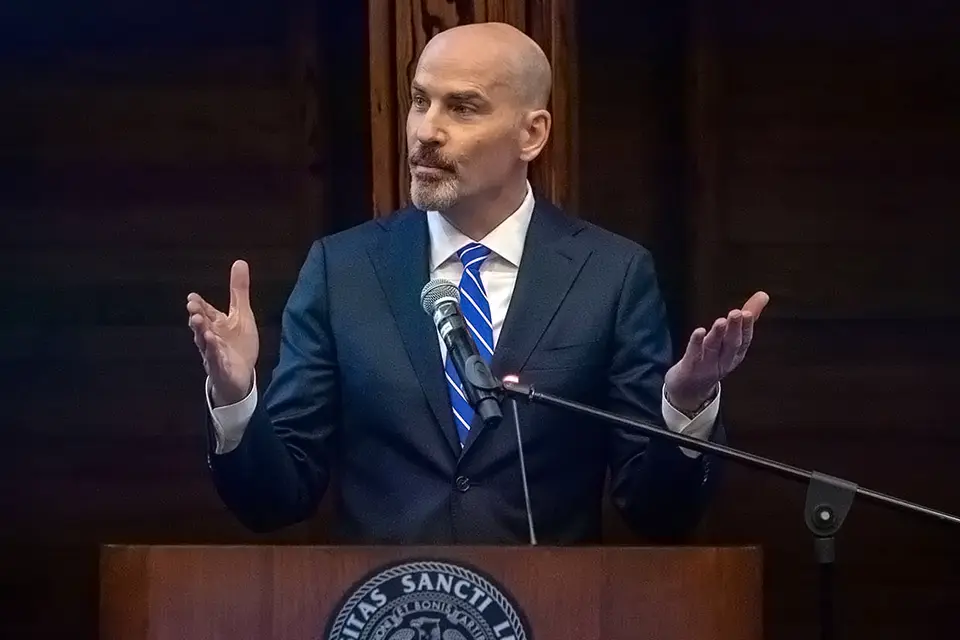 A person in a suit and tie standing at a podium with a microphone.