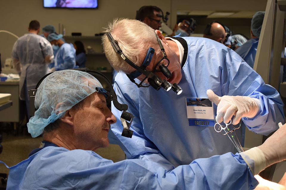 PASE doctors wearing medical equipment and personal protective gear examine a cadaver.