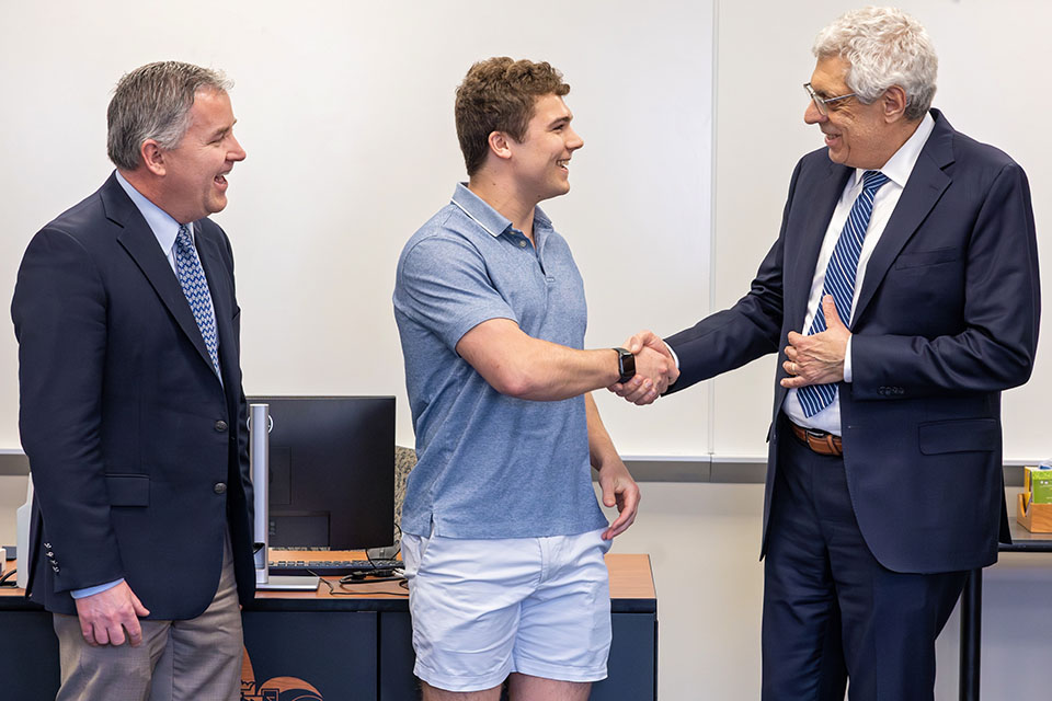 Sam Aitchison, center, shakes hands with President Fred P. Pestello, Ph.D., right.  Provost Mike Lewis, Ph.D., left, is also pictured.